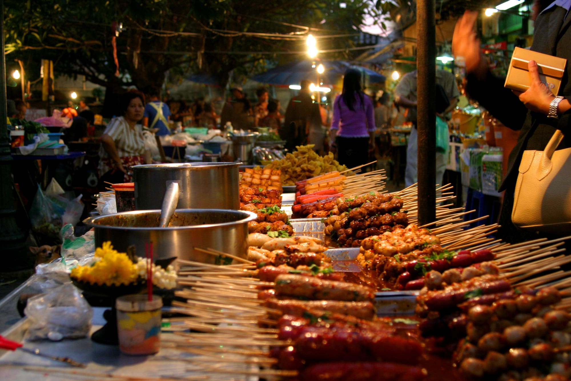 A night street-food market in Asia: grills lined with skewers under string lights